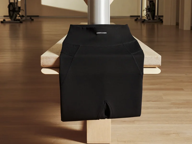 Hochgeschnittene schwarze Trainingsleggings gefaltet auf einer hellen Holzbank